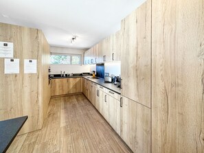 Eine moderne Küche mit Holzschränken, einer schwarzen Arbeitsplatte und einem Fenster, das für natürliches Licht sorgt.