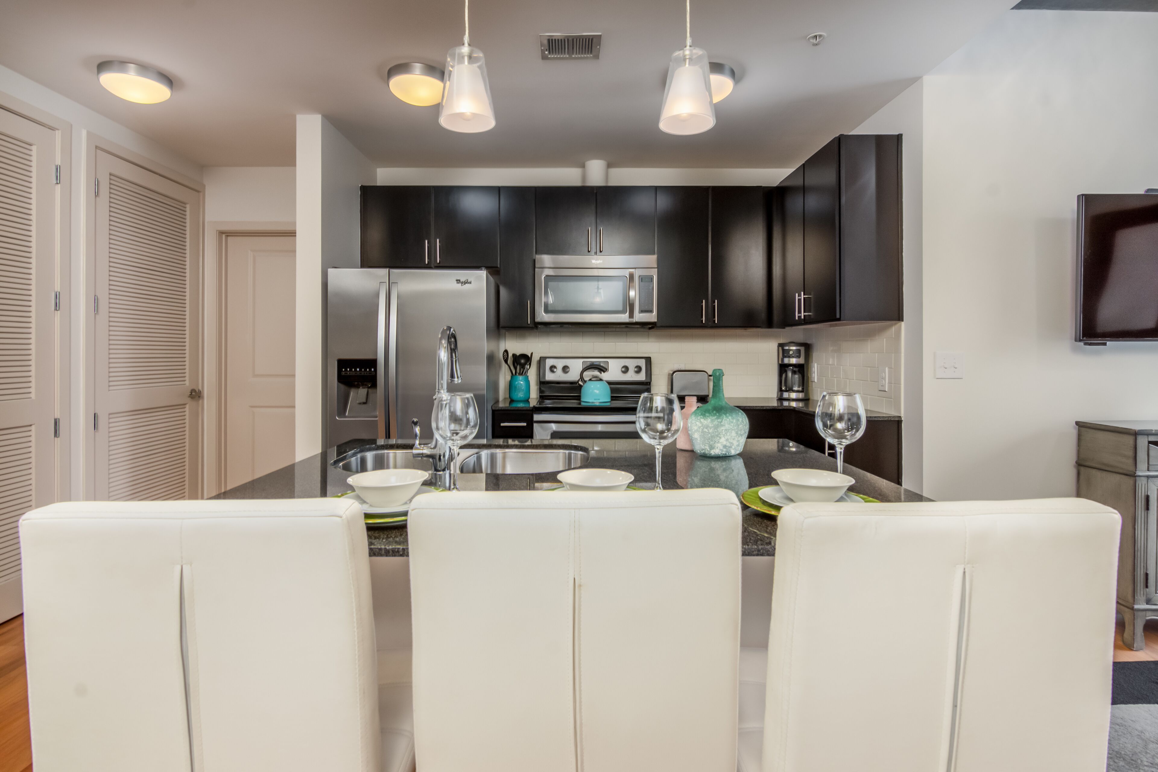 A modern kitchen with dark cabinets, stainless steel appliances, and a central island with seating.