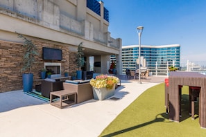 An outdoor patio with seating, a fire pit, and a large planter with flowers.