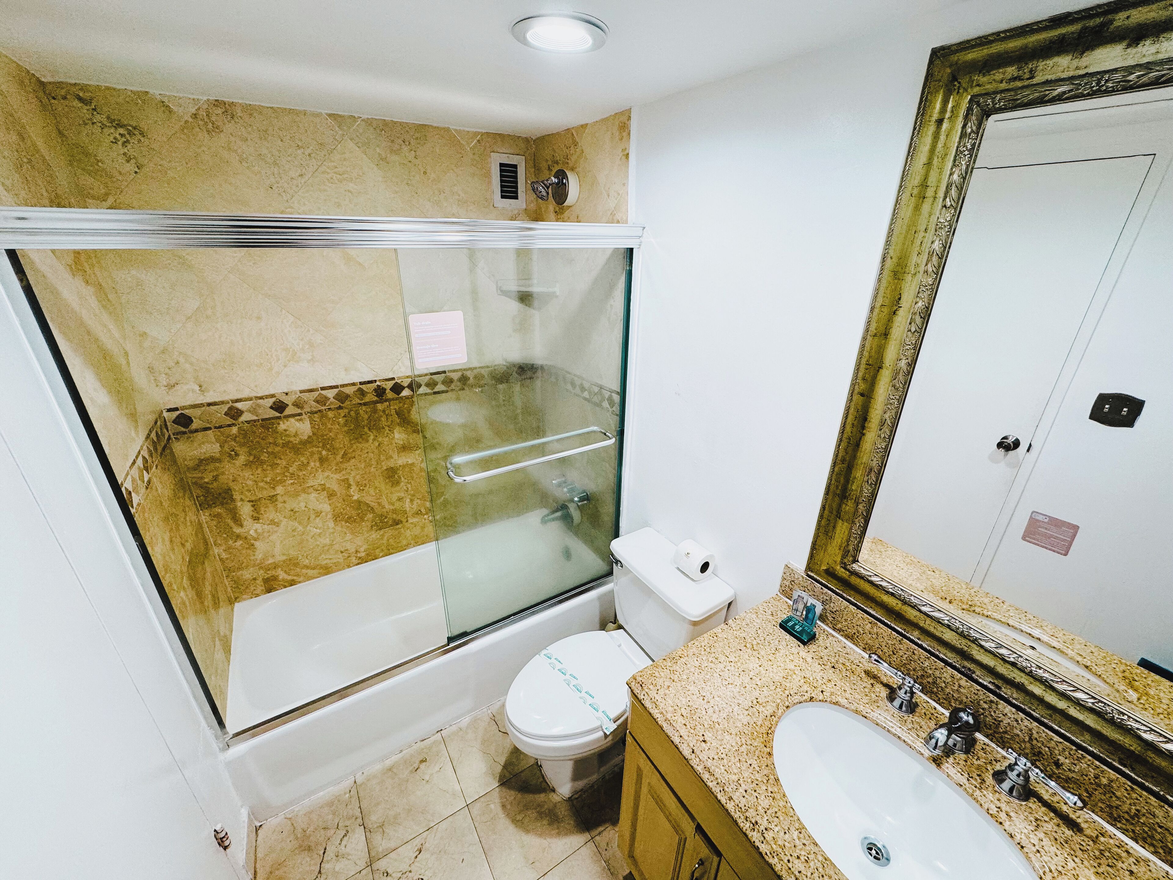 Une salle de bain avec une douche à parois de verre, des toilettes, un lavabo et un grand miroir.