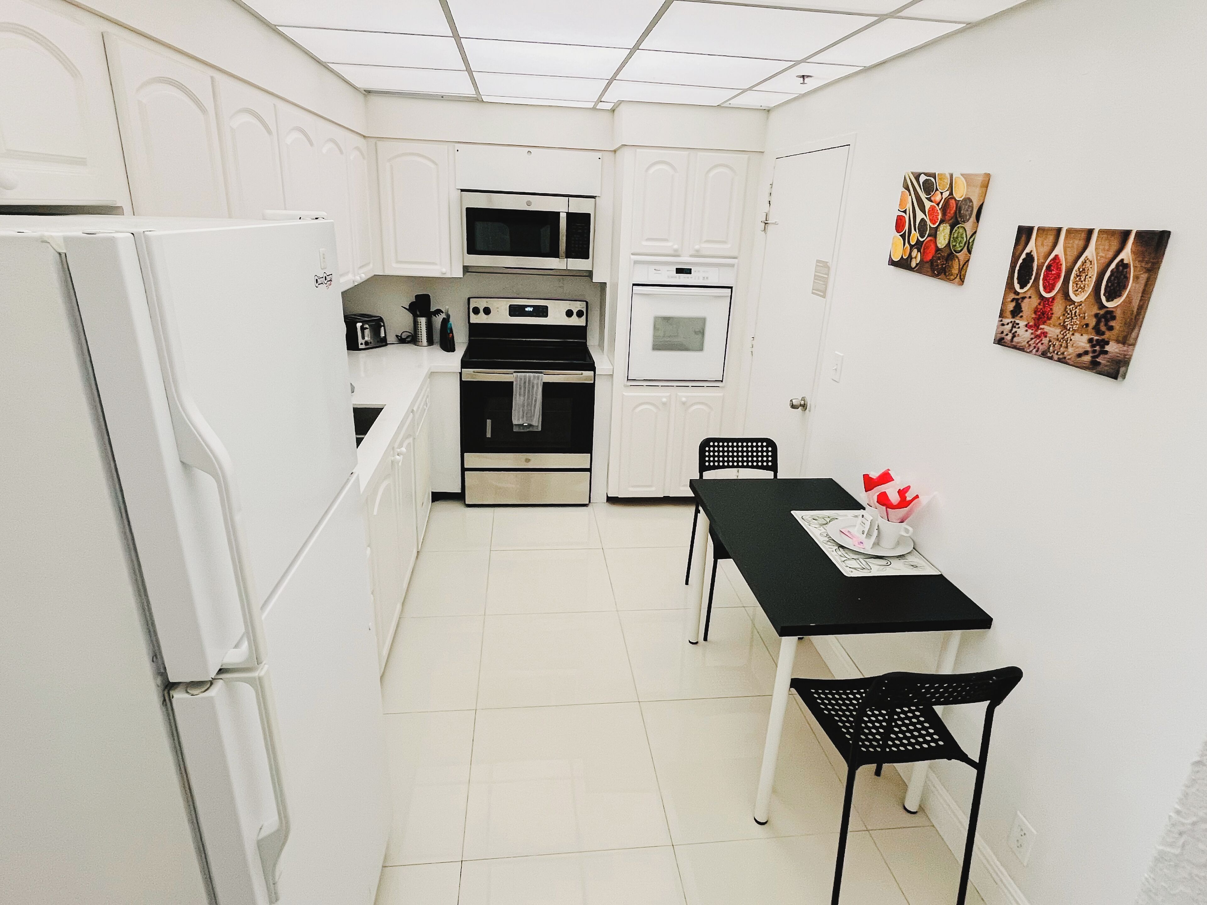 A compact kitchen with white cabinets, a black stove, a microwave, and a table with chairs.