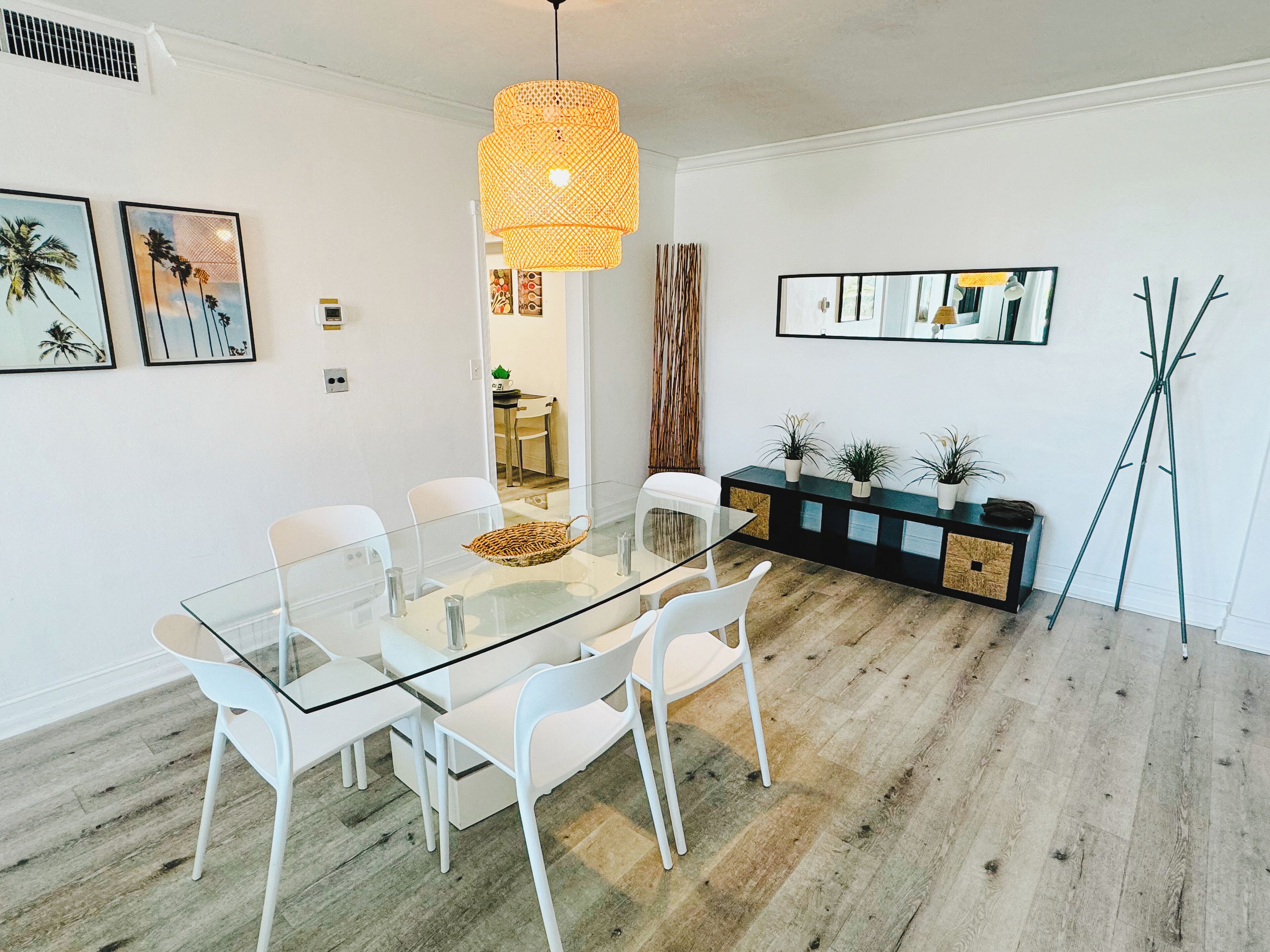 A modern dining area with a glass table, white chairs, and a central hanging light fixture.