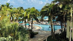 A pool area with palm trees, lounge chairs, and a clear sky. - The Tides on Hollywood (Hollywood)