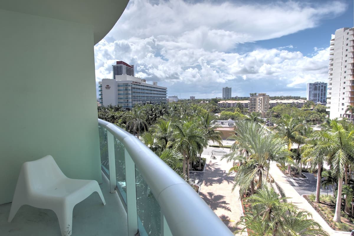 A balcony with a view of a cityscape, including tall buildings and palm trees.