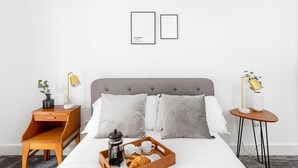 A neatly arranged bedroom with a bed, bedside tables, a bedside lamp, a tray with breakfast items, and framed artwork on the wall. - Beautiful Apartment in Central Neighbourhood (Cardiff)