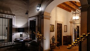 Un corridoio illuminato con calore, con un tavolo, libri, un vaso e una scala decorata con candele.