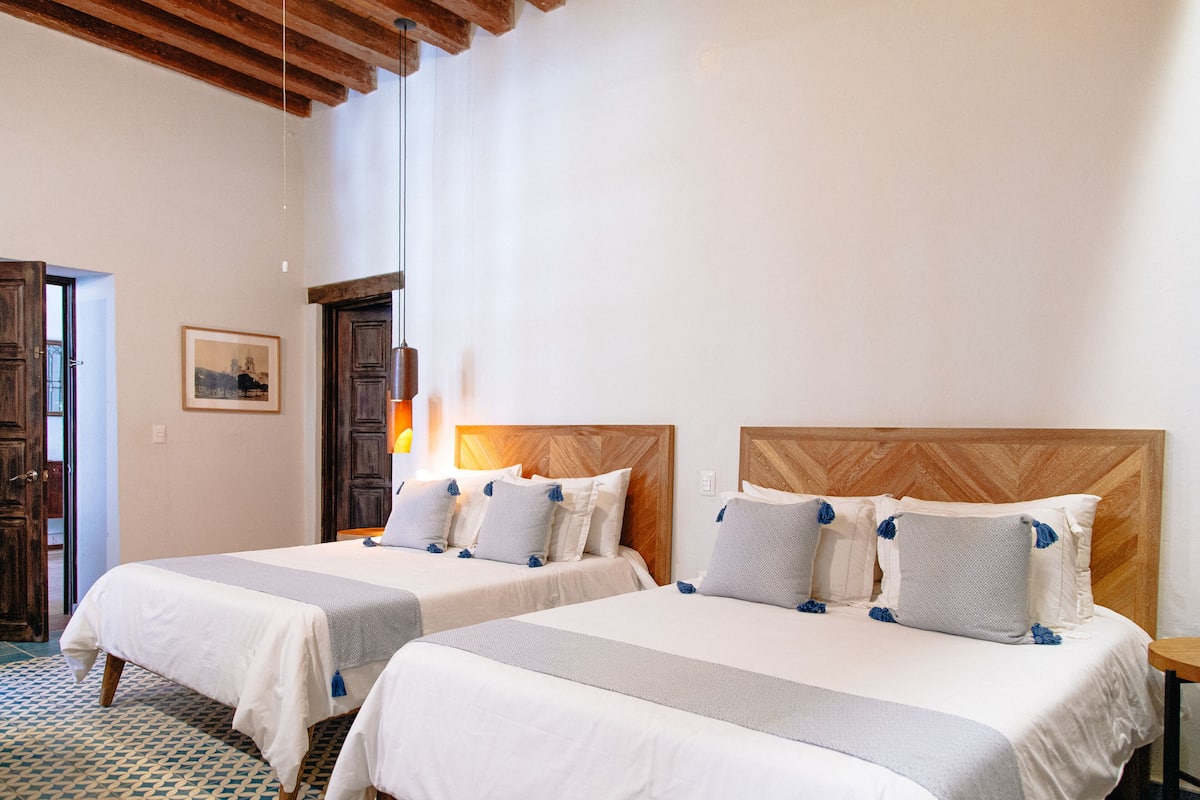 A hotel room with two beds, wooden headboards, and a patterned floor.