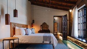 Una camera da letto con un letto, un comodino, luci a sospensione, pavimento decorato e una finestra con tende.