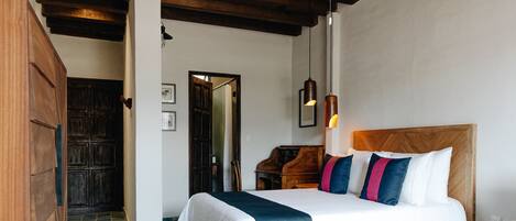 Habitación de hotel con dos camas, vigas de madera en el techo, un piano y suelo de baldosas.