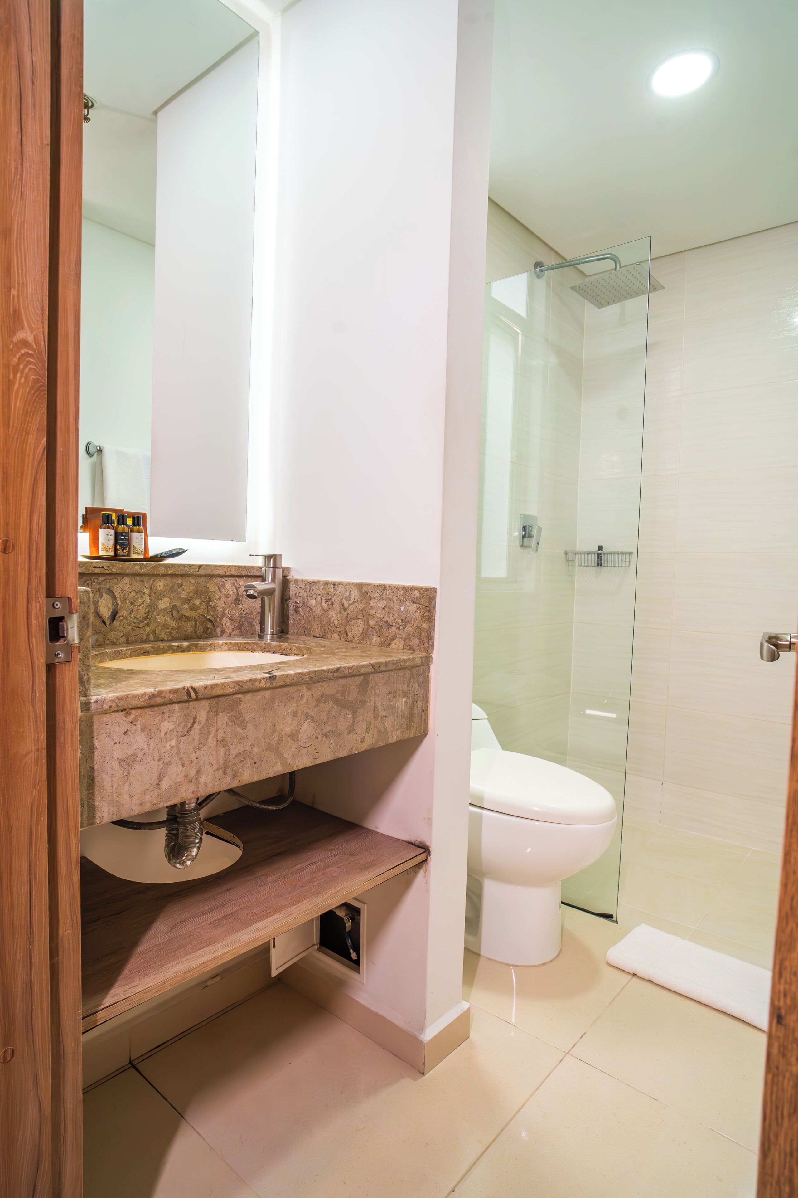 Un baño con lavamanos de mármol, inodoro y cabina de ducha de vidrio.