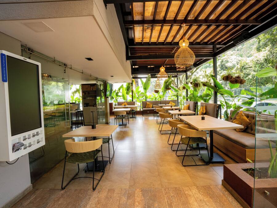 A modern restaurant with glass walls, wooden ceiling, and various seating arrangements.