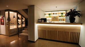 Un área de recepción con mostrador de madera, una escalera y una planta en maceta.