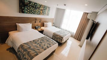 Habitación de hotel con dos camas, un cuadro grande en la pared, un teléfono y una ventana con cortinas.