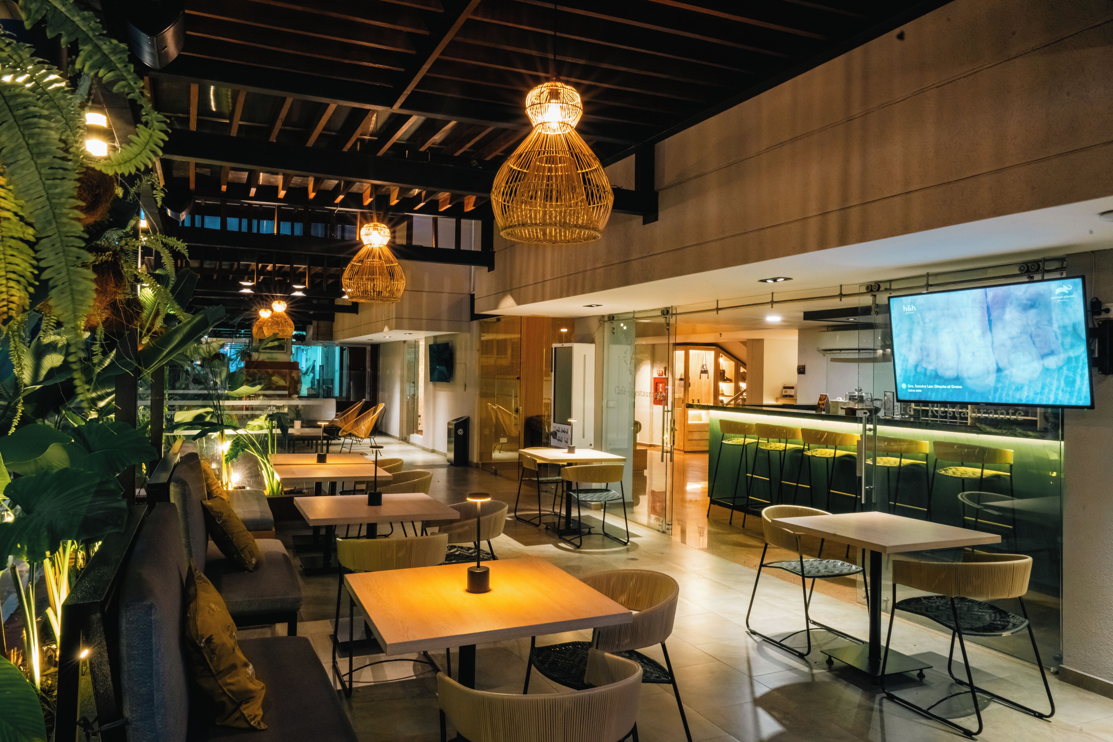 A modern interior with seating areas, hanging lights, and a large screen.