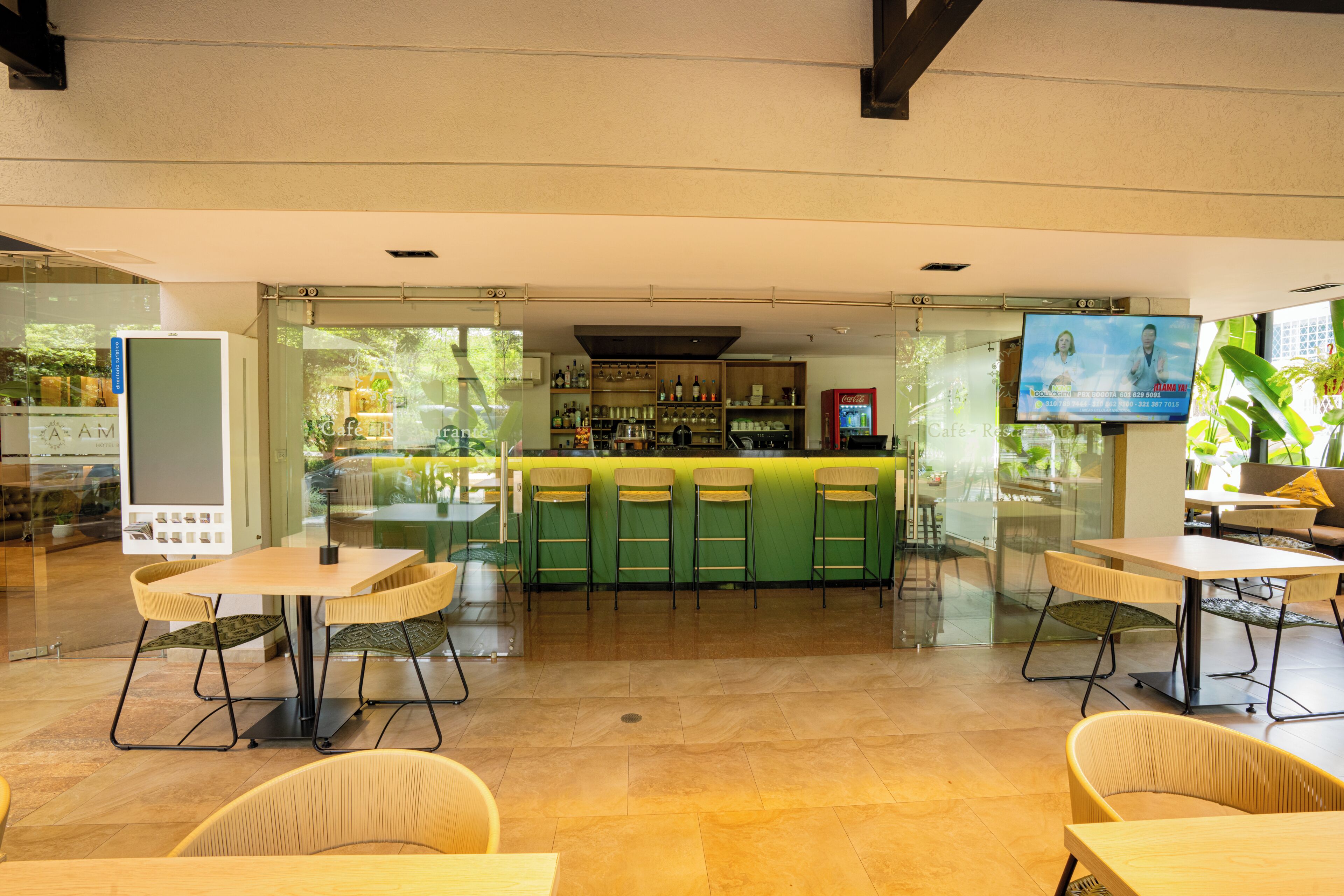 Un área de bar moderna con mostrador verde, varios taburetes y una pantalla de televisión.