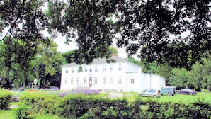 Et stort, flerlags hotel med en symmetrisk facade, omgivet af frodig vegetation og en velplejet græsplæne.