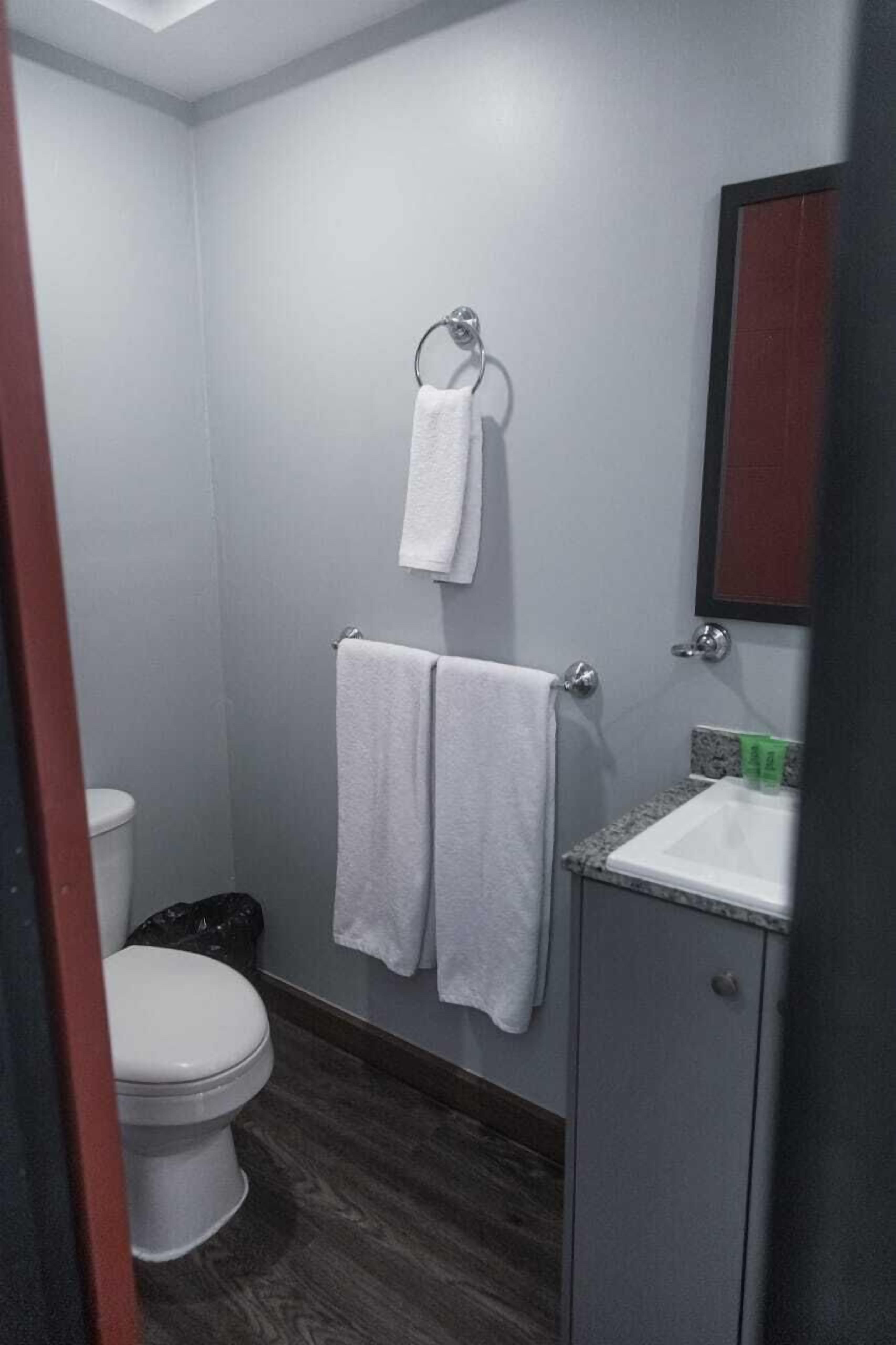 Un baño pequeño con inodoro, lavamanos y dos toallas colgadas en la pared.