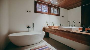 Une salle de bain moderne avec une grande baignoire sur pieds, un meuble-lavabo en bois et un grand miroir.