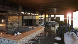 A modern outdoor bar area with stone walls, seating, and a view of the sunset. - AC Hotel by Marriott Bridgewater (Bridgewater)