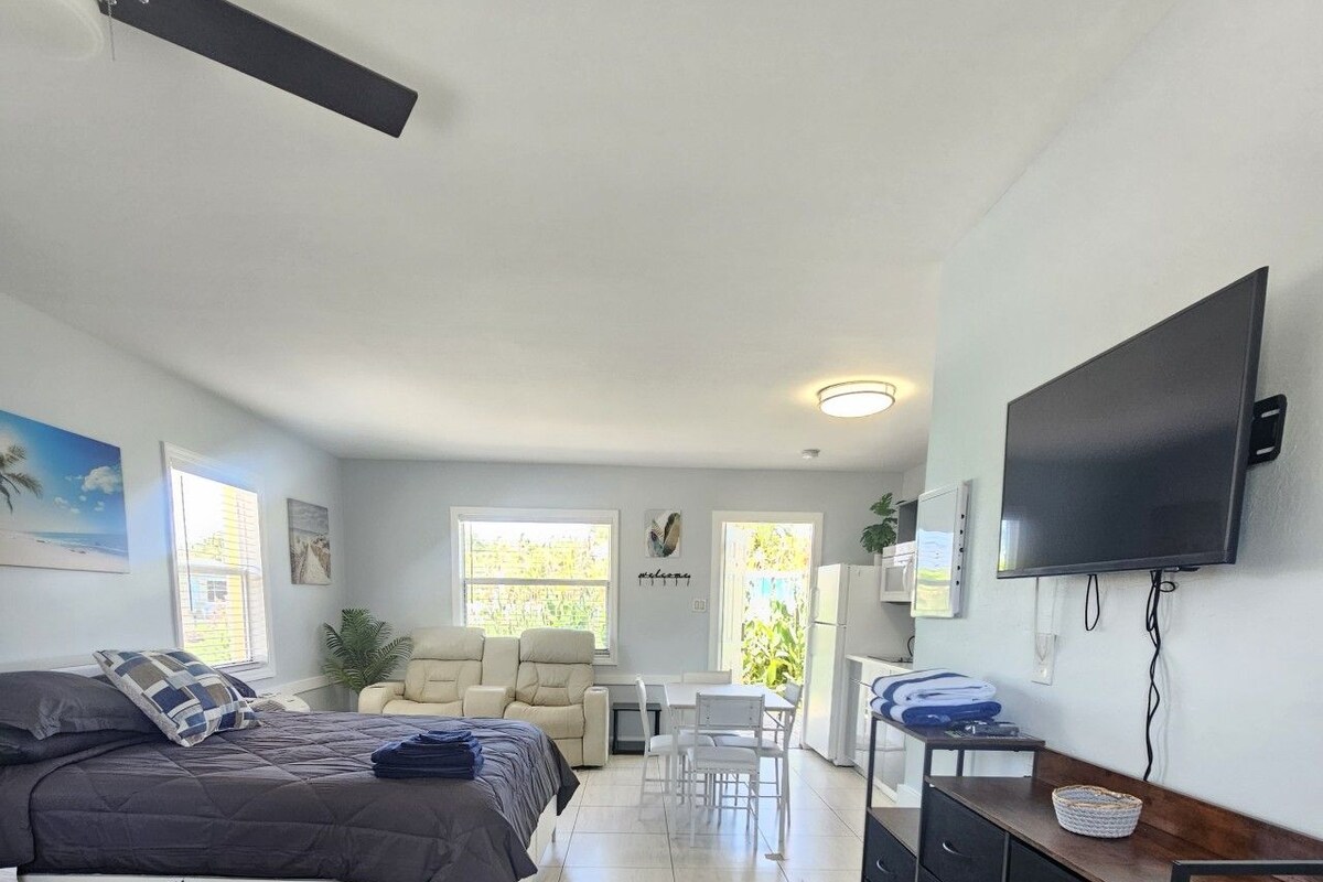 A room with two beds, a desk, a TV, and a dining area.