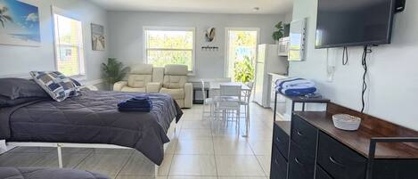 Una habitación con dos camas, un escritorio, un televisor y una zona de comedor.