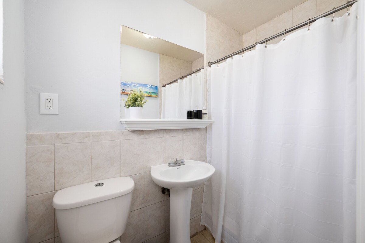 A bathroom with a toilet, sink, and shower curtain.