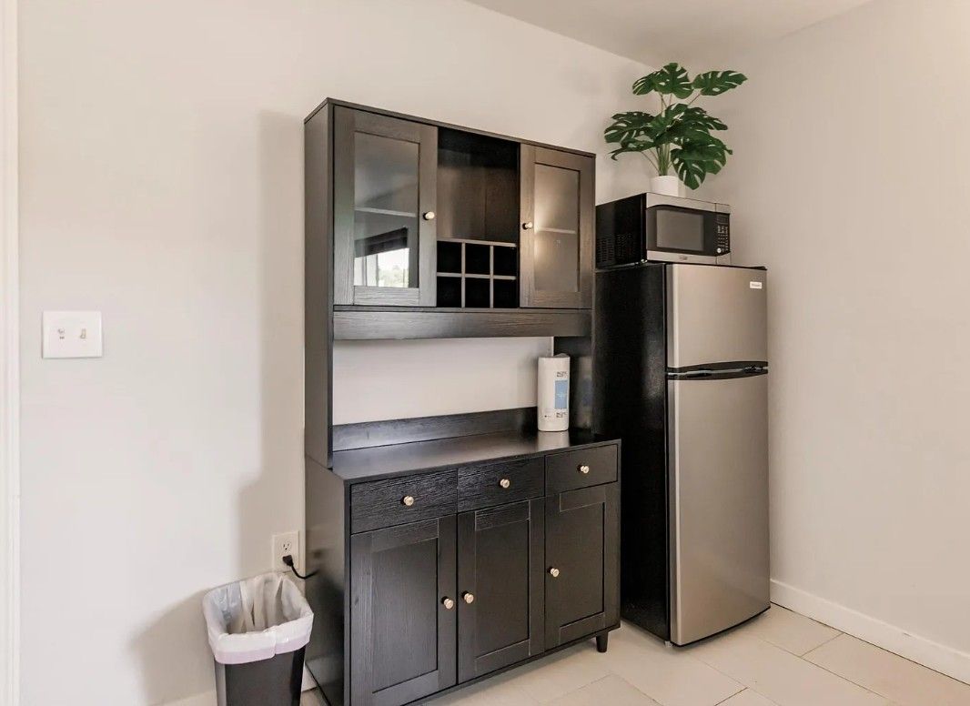 A kitchen with a built-in microwave, a refrigerator, and a cabinet with drawers.