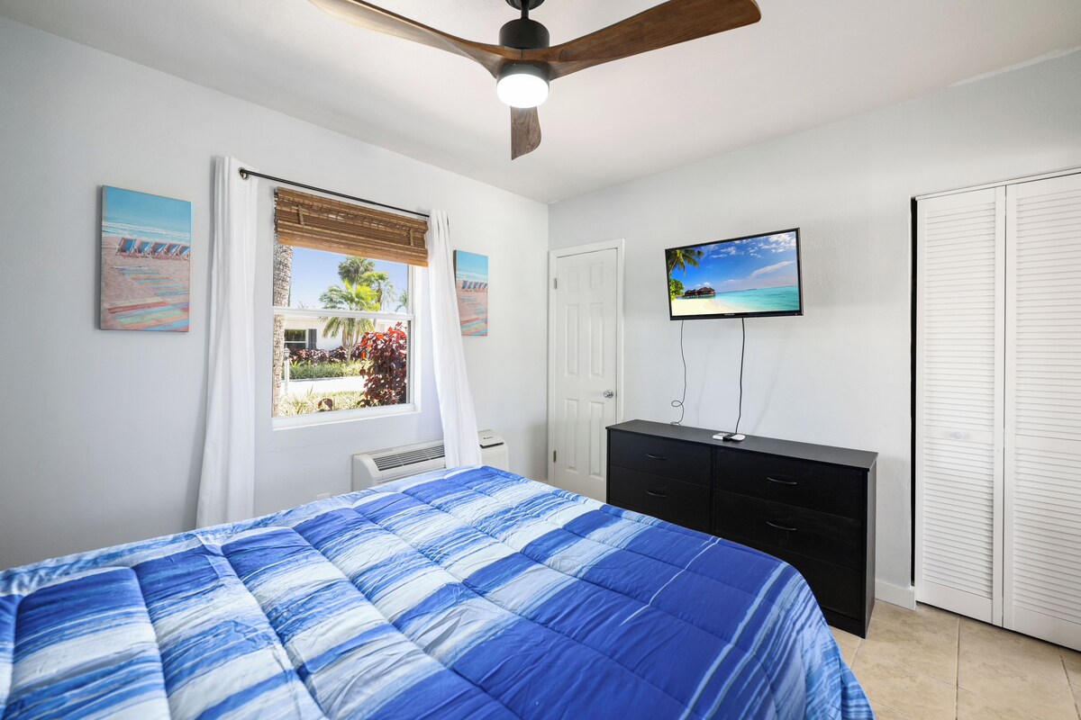 A bedroom with a bed, a TV, a wardrobe, and a ceiling fan.