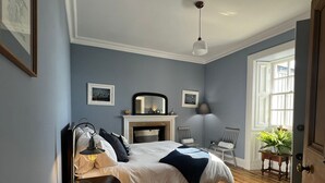 A bedroom with a bed, a bedside table, a lamp, a mirror, a fireplace, and a window. - Adventure awaits you on your very own private island off Skye! (Isle of Skye)
