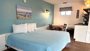 A bedroom with a bed, a desk, and a kitchenette. - Nautical Motel (Hampton)