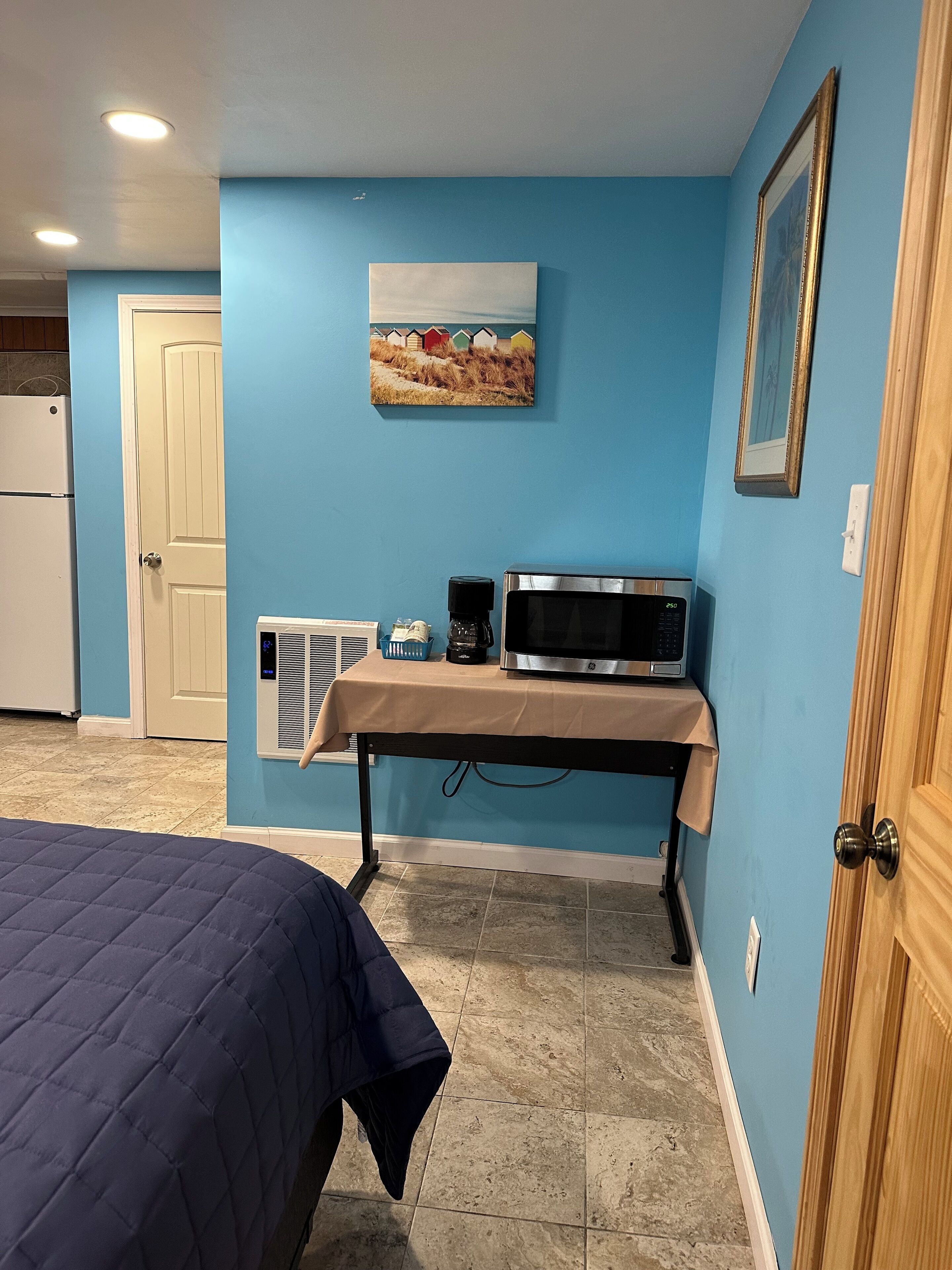 Une chambre avec un lit, un four à micro-ondes, une machine à café et un tableau au mur.