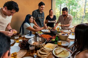 A group of people gathered around a table with various dishes and drinks, indicating a communal meal setting. - Cabaña lujo Alberca climatizada (Mazamitla)