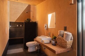 A compact bathroom with a toilet, sink, and shower. A towel rack and a basket with towels are visible. - Cabaña lujo Alberca climatizada (Mazamitla)