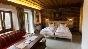 A room with two beds, a wooden table, and a bench. - Landhaus Griessee (Obing)