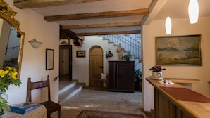 A traditional interior with exposed wooden beams, a staircase, a wooden cabinet, and a painting on the wall. - Landhaus Griessee (Obing)