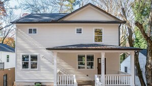 A two-story house with a front porch, a small front yard, and a mailbox. - Mega Master Suite 4 miles to Mercedes Benz Stadium (4 Smart TVs) (Atlanta)