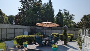 Eine Terrasse mit Tisch und Stühlen, eine Holzterrasse und ein weißer Zaun.