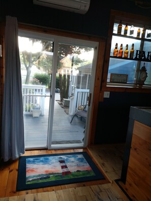 A room with a sliding glass door leading to a deck, a bar area with bottles, and a framed sign on the door.