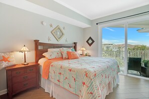 Une chambre à coucher avec un lit, des tables de chevet et un balcon offrant une vue.