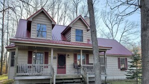Een tweelaags huis met een veranda, een voordeur en een kleine trap naar de ingang.
