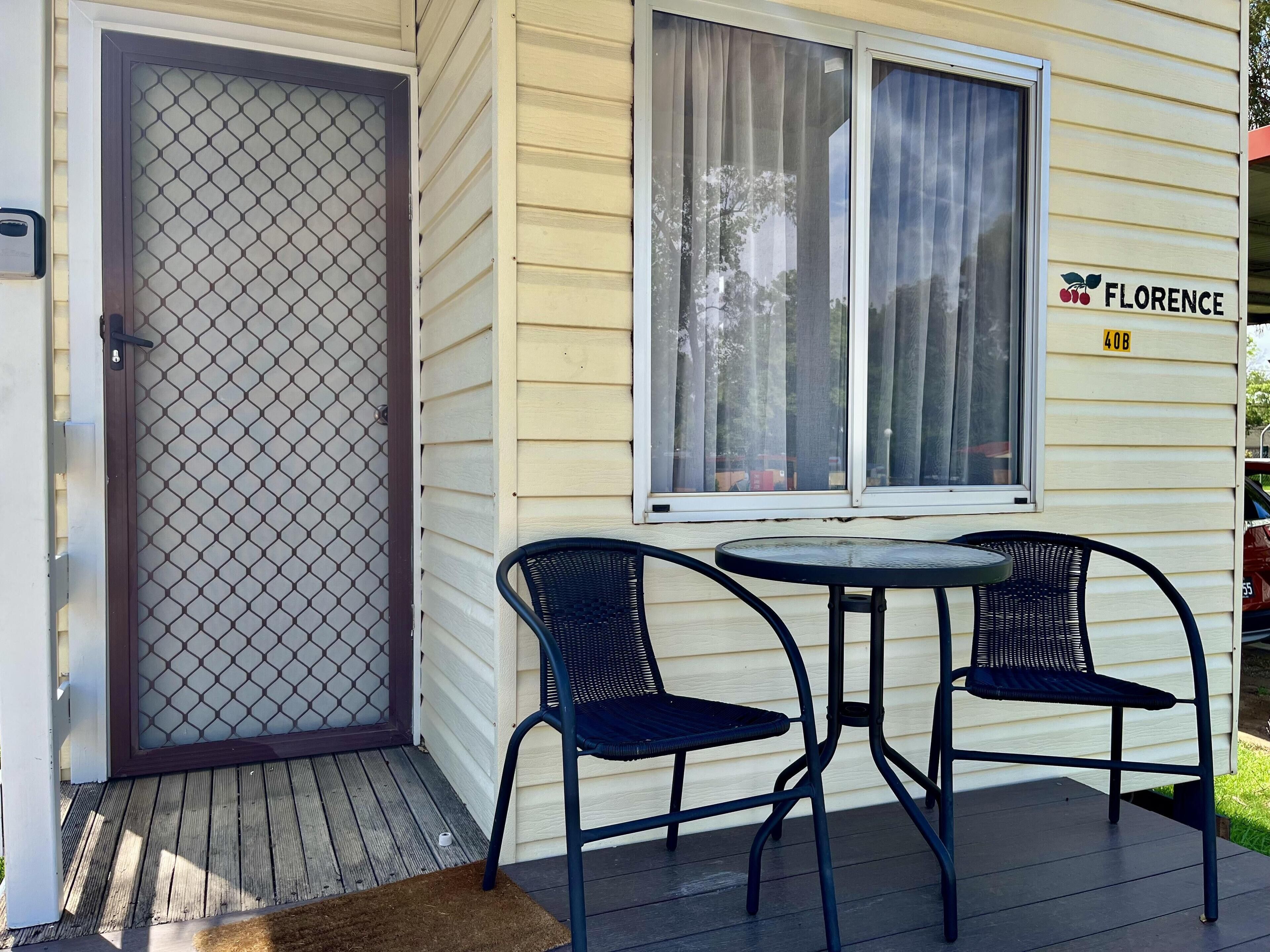 A house with a screened door, a porch with two chairs and a table, and a sign reading "FLORENCE 40B".