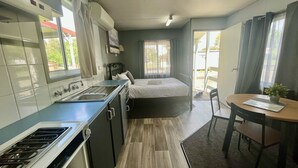A compact room with a kitchenette, a bed, and a dining area. - Young Tourist Park (Young)