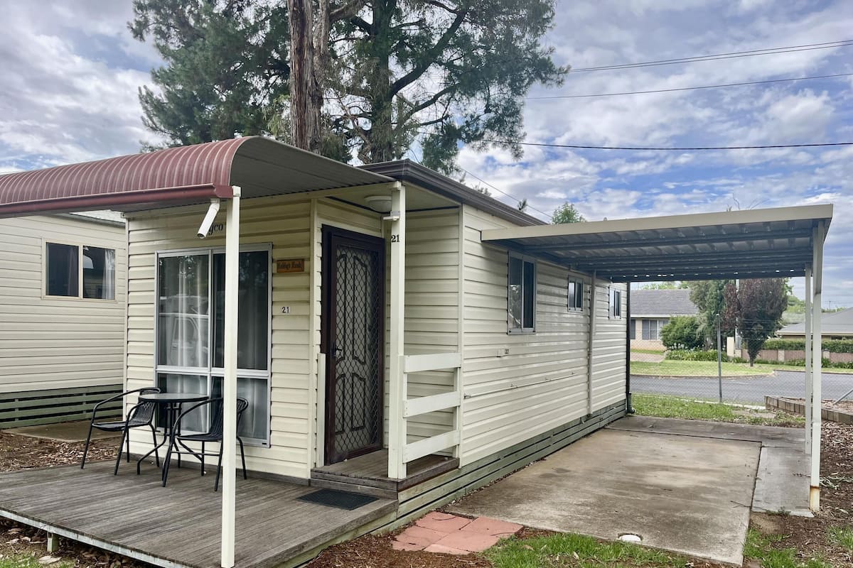 A single-story mobile home with a covered porch, a small patio, and a fenced yard.