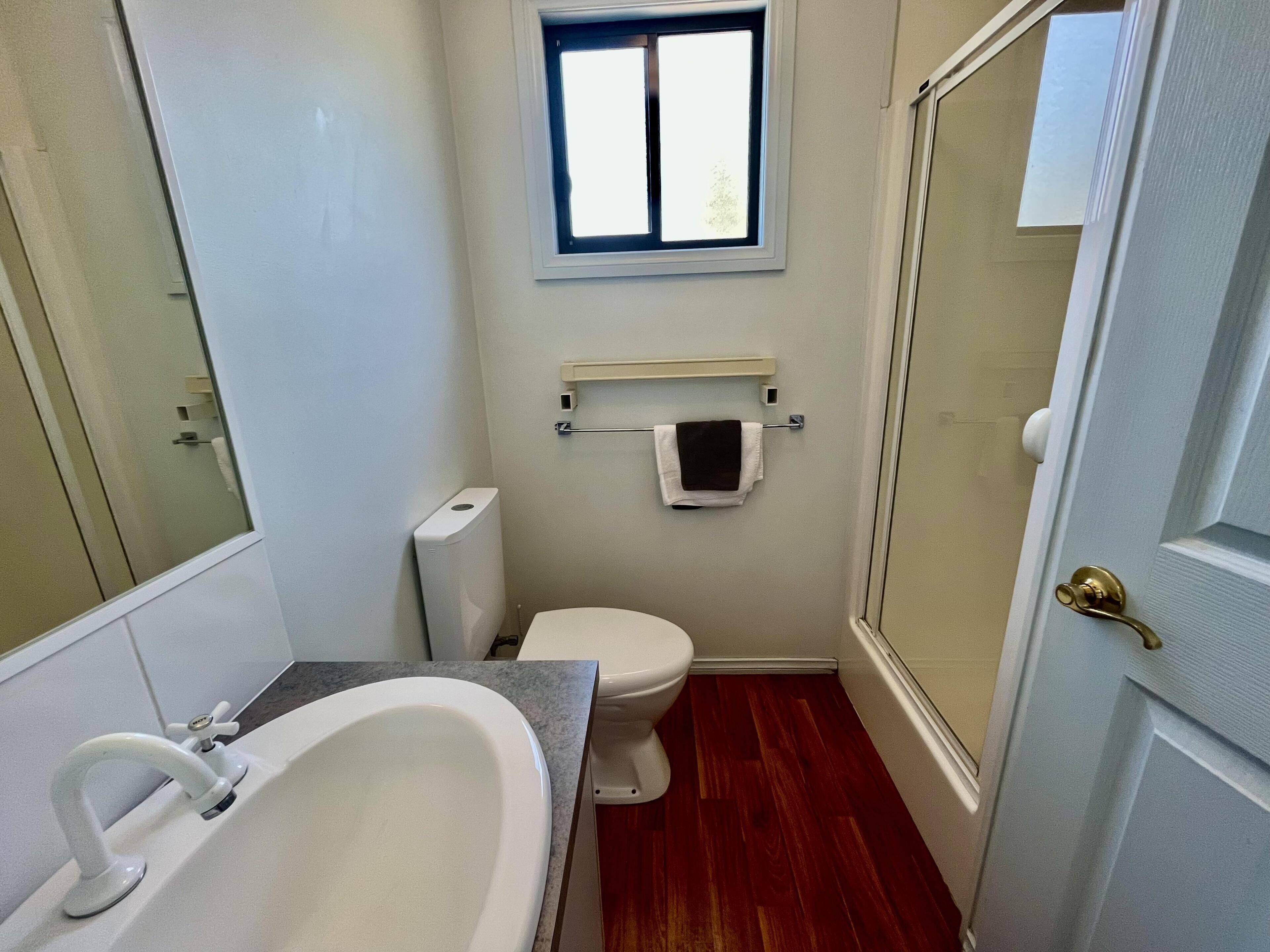 A bathroom with a bathtub, toilet, and window.