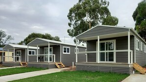 A row of modern, two-story mobile homes with large windows and a covered porch area. - Young Tourist Park (Young)