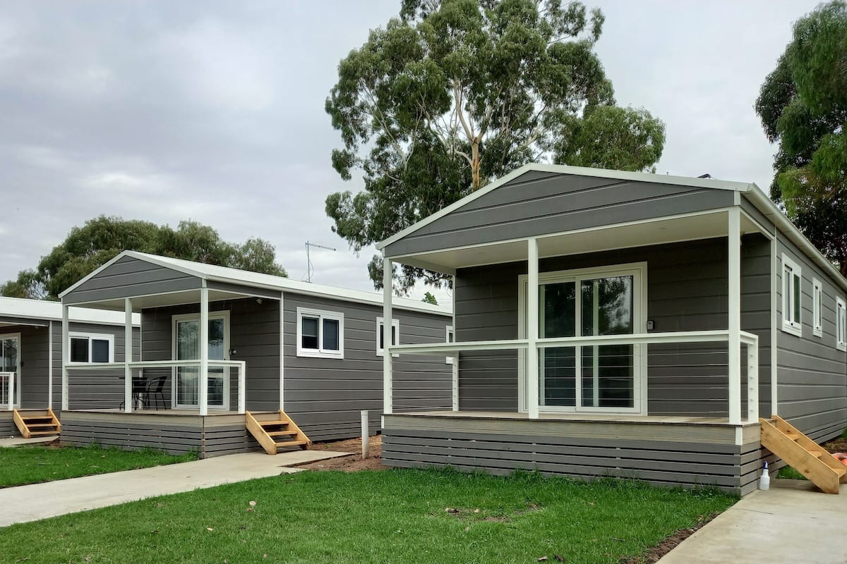 A row of modern, two-story mobile homes with large windows and a covered porch area.