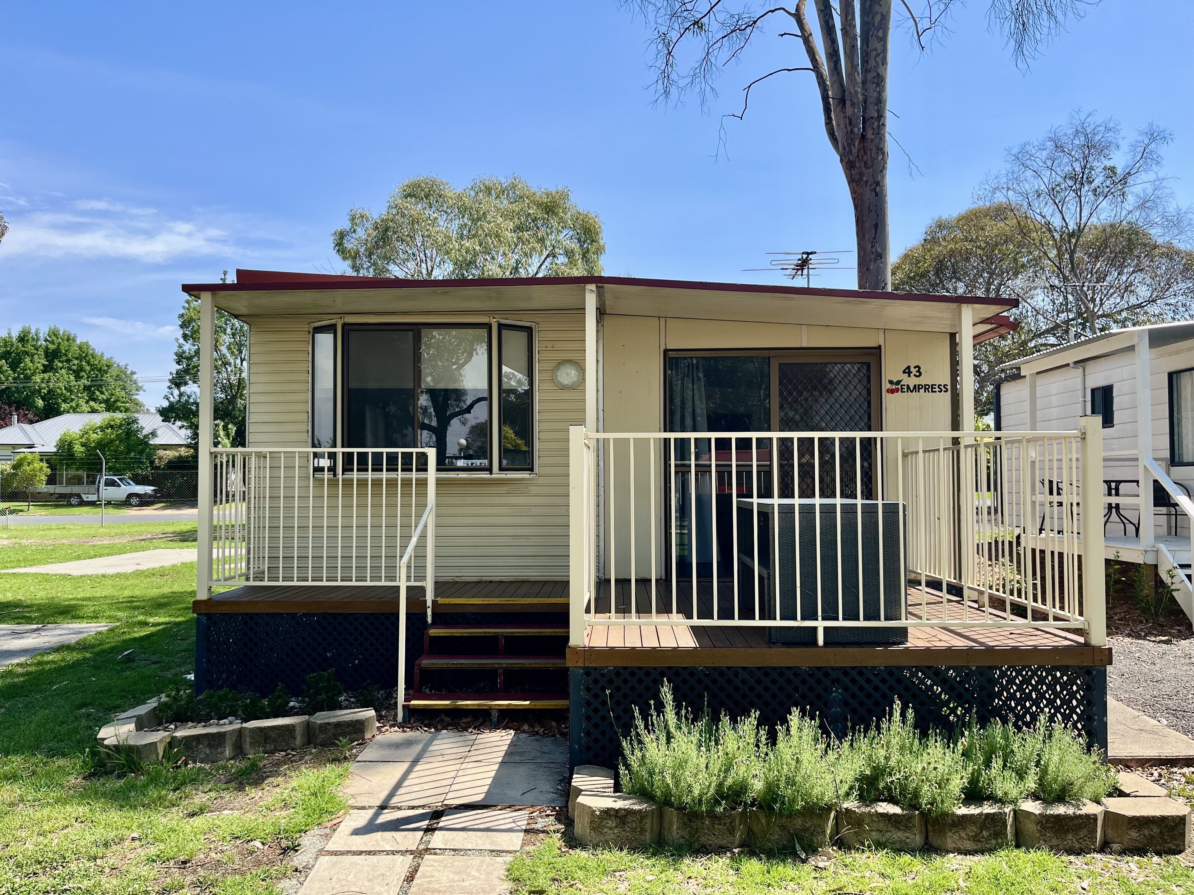A small, single-story mobile home with a porch and a small deck.