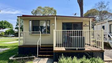 A small, single-story mobile home with a porch and a small deck.
