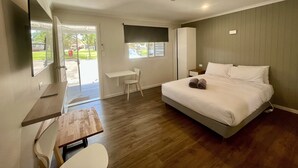 A bedroom with a bed, a desk, a chair, a TV, and a window. - Young Tourist Park (Young)