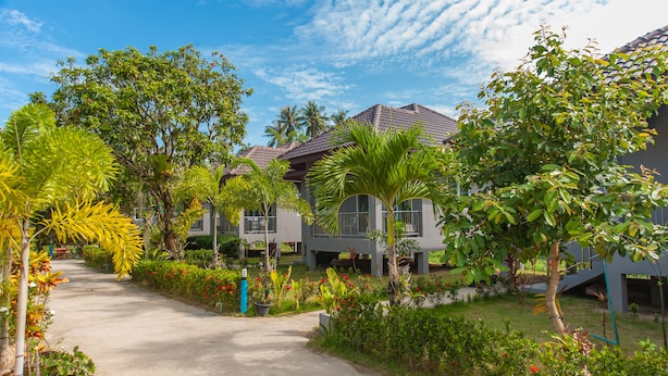 A pathway leading to a building with multiple balconies, surrounded by lush greenery and palm trees. - Cozy cottage with kitchen of Maenam 4 (Koh Samui)